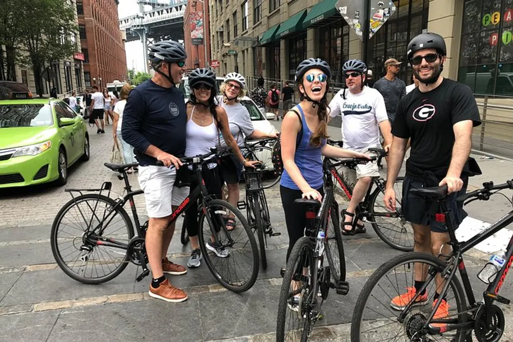 A group of cheerful cyclists wearing helmets are standing with their bikes on an urban street possibly taking a break during a ride