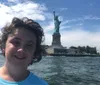 The image is a panoramic view of the Manhattan skyline as seen from a boat on the water featuring clear skies and a few clouds above