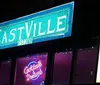 A man holding a microphone speaks to a woman on a stage with a sign that reads EASTVILLE Est 2008 in the background