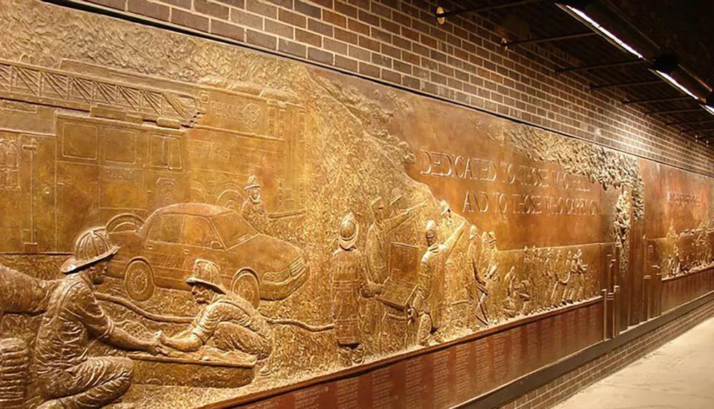 The image shows a large bronze relief mural depicting firefighters in various scenes of action and heroism with text indicating dedication to these individuals