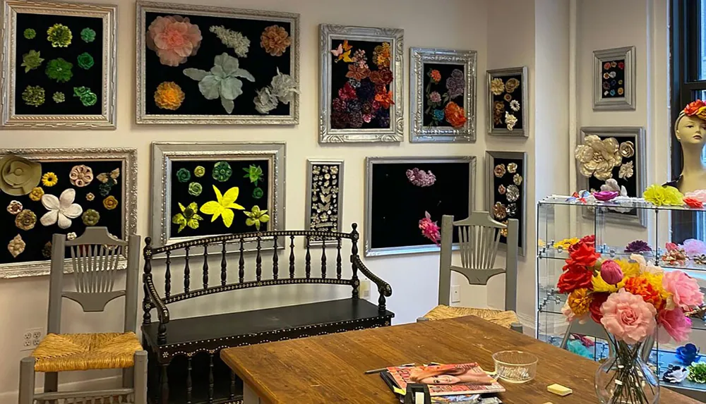 An eclectic flower-themed interior features various framed flower displays on the walls colorful blooms on display stands and a mannequin head wearing a floral accessory