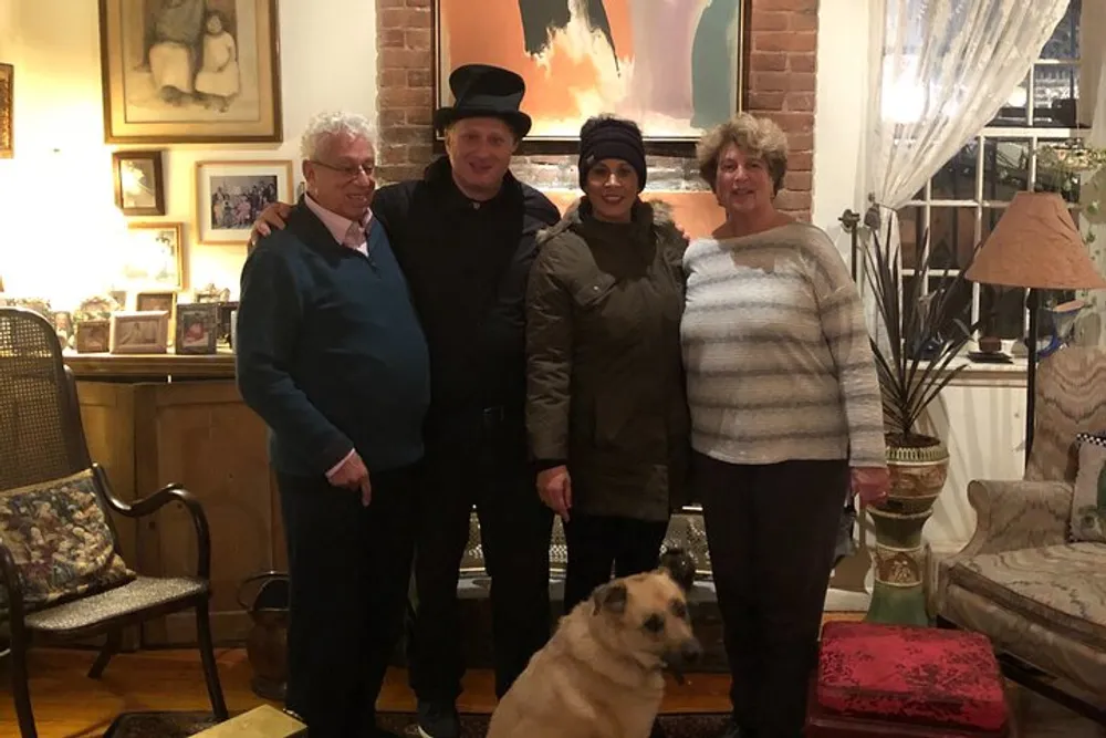 Four people and a dog are posing for a photo in a warmly decorated living room