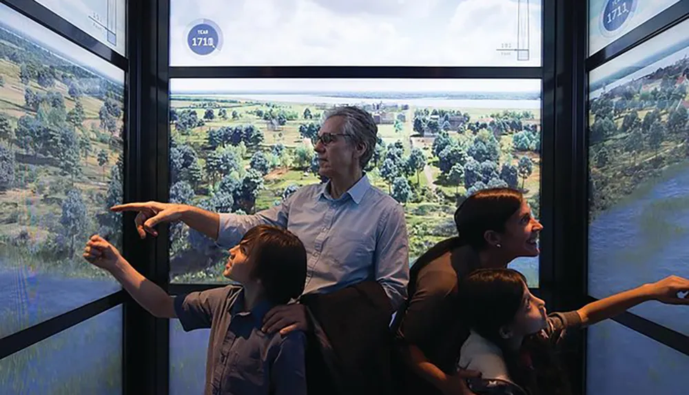 A group of people including a child are looking out through a large window with nature views pointing and expressing interest in what they see