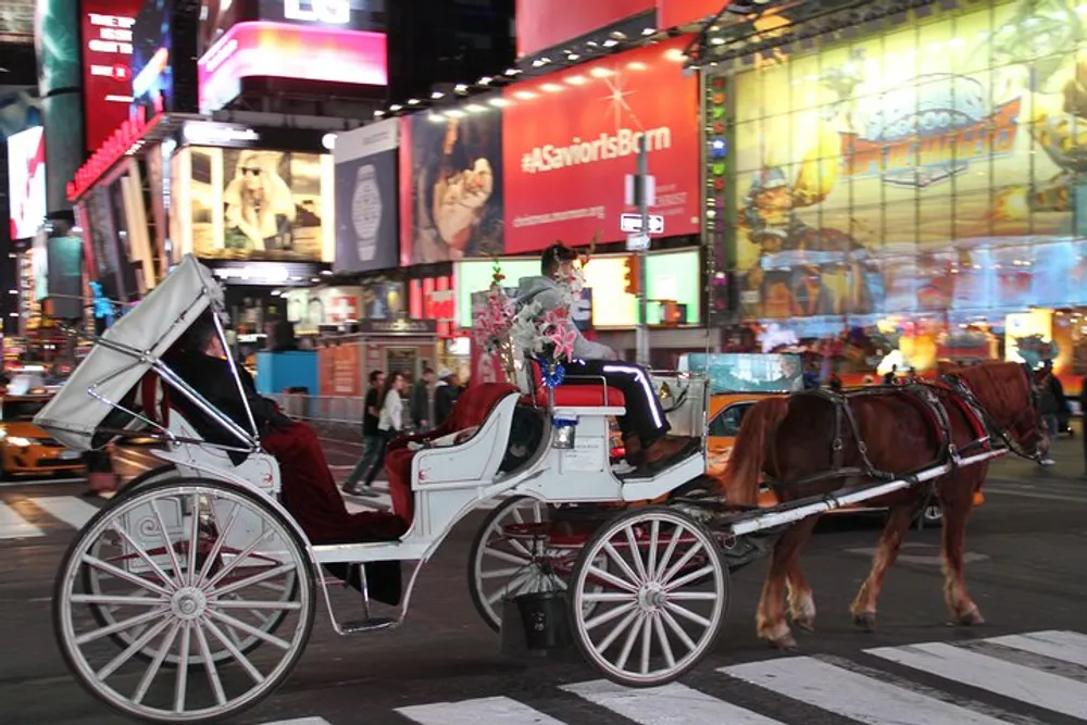 A horse-drawn carriage is passing through a brightly lit bustling Times Square at night