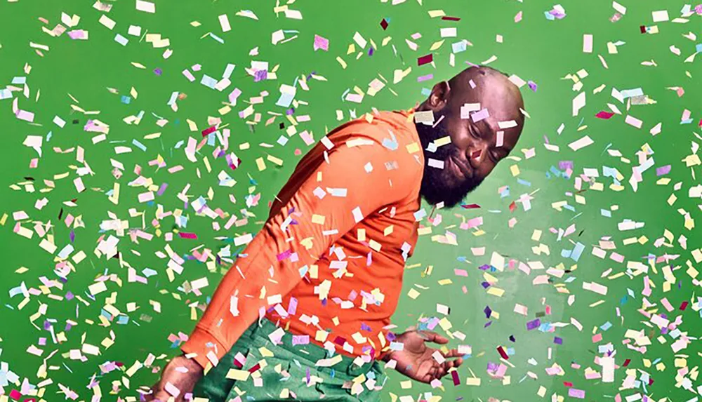 A person is immersed in a joyful moment with confetti flying all around on a green background