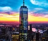 The image features the One World Trade Center skyscraper in New York City against a dramatic sunset with a view of the Hudson River and the surrounding urban landscape