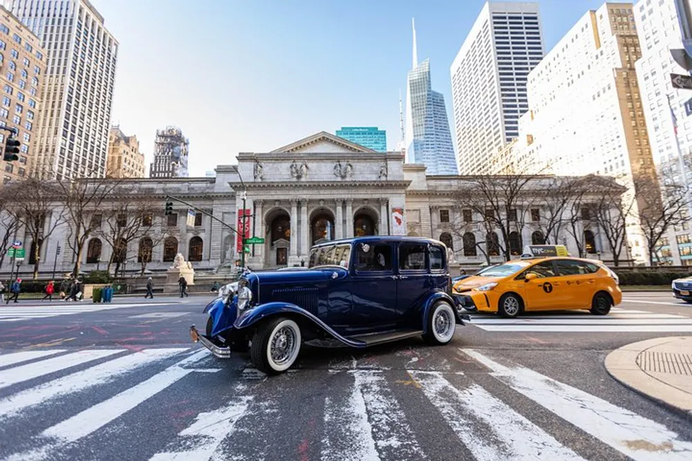 A vintage blue car is parked on a city street with pedestrian crosswalks contrasting with a modern yellow taxi in front of a stately building with classical architecture