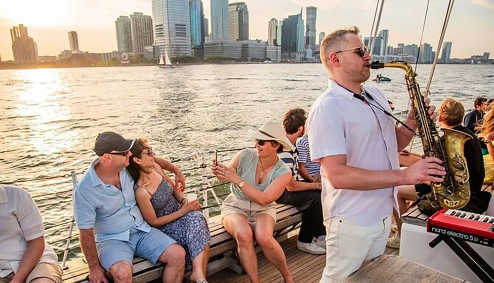 A man plays the saxophone on a boat with a small audience enjoying the music and the skyline in the background during a sunset