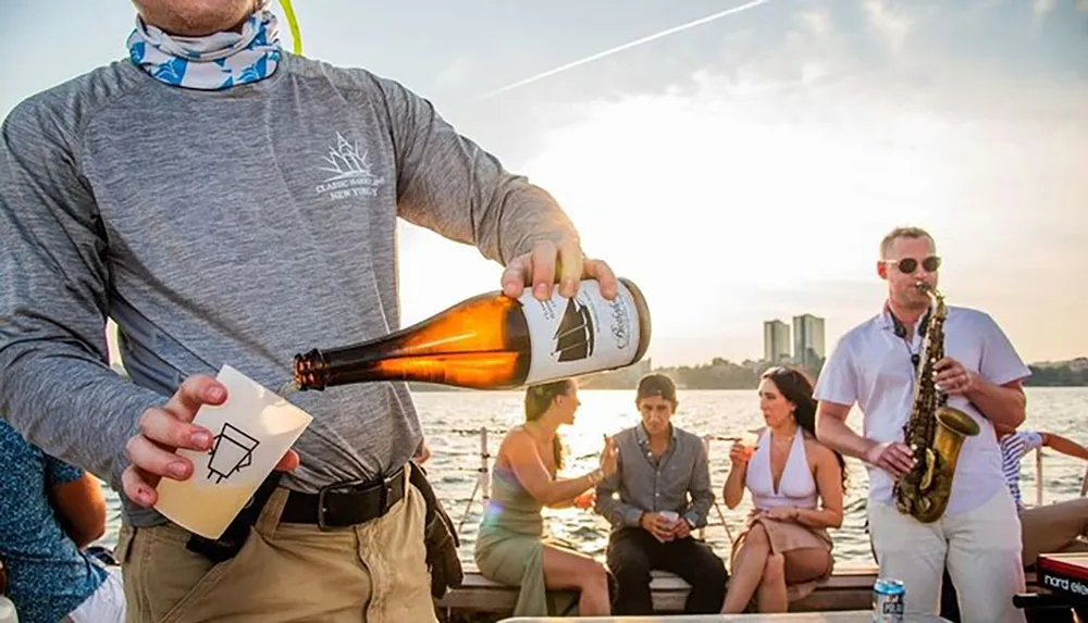 A person is pouring a drink while others enjoy a social gathering on a boat with one individual playing the saxophone