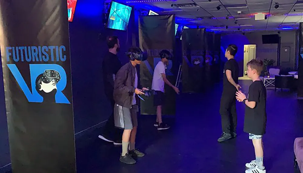 Several individuals are enjoying a virtual reality VR experience in an indoor setting adorned with banners that read Futuristic VR