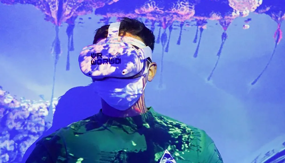 A person is immersed in a virtual reality experience wearing a headset against a backdrop with jellyfish-like visuals