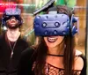 Two people are wearing VR headsets and appear to be delighted by their immersive virtual reality experience