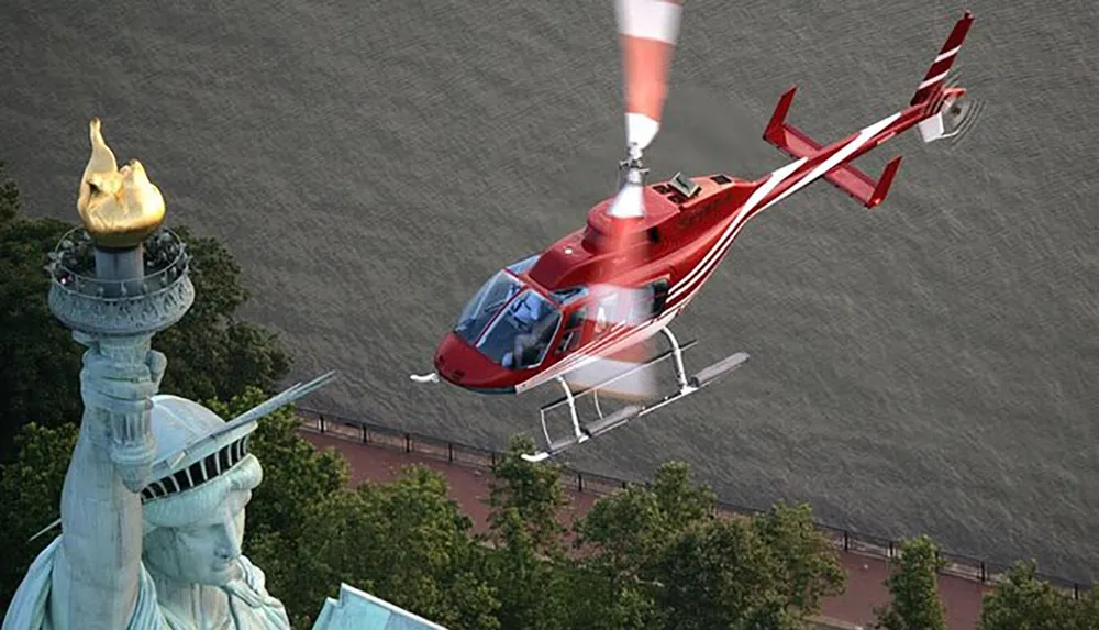 A red helicopter is flying near the Statue of Liberty