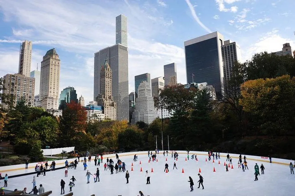 People are enjoying ice skating at an outdoor rink framed by the skyscrapers of a bustling city
