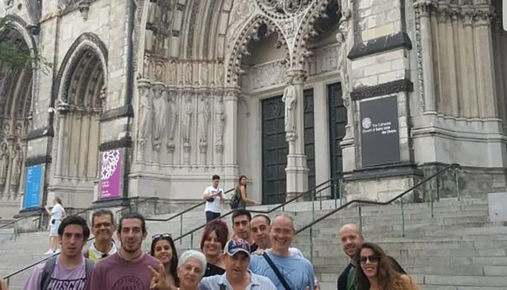 A group of cheerful people is posing for a photo in front of an ornate cathedral entrance with Gothic architectural details