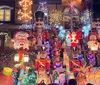 The image shows a house festively decorated with an abundance of Christmas lights and various holiday figures including Santa Claus nutcrackers and snowmen