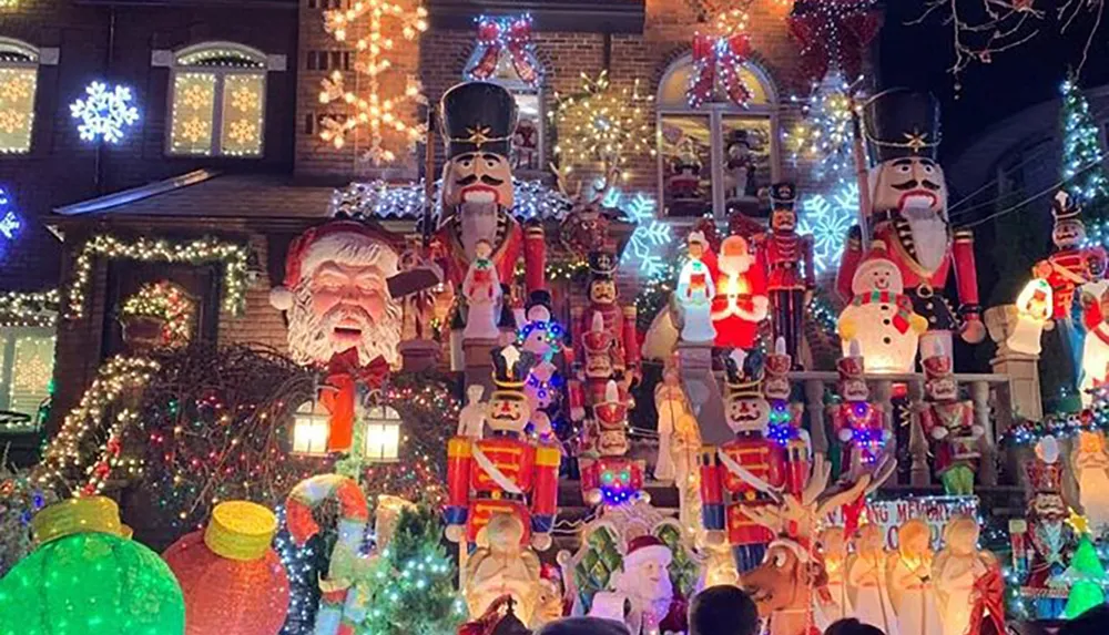 The image shows a house festively decorated with an abundance of Christmas lights and various holiday figures including Santa Claus nutcrackers and snowmen