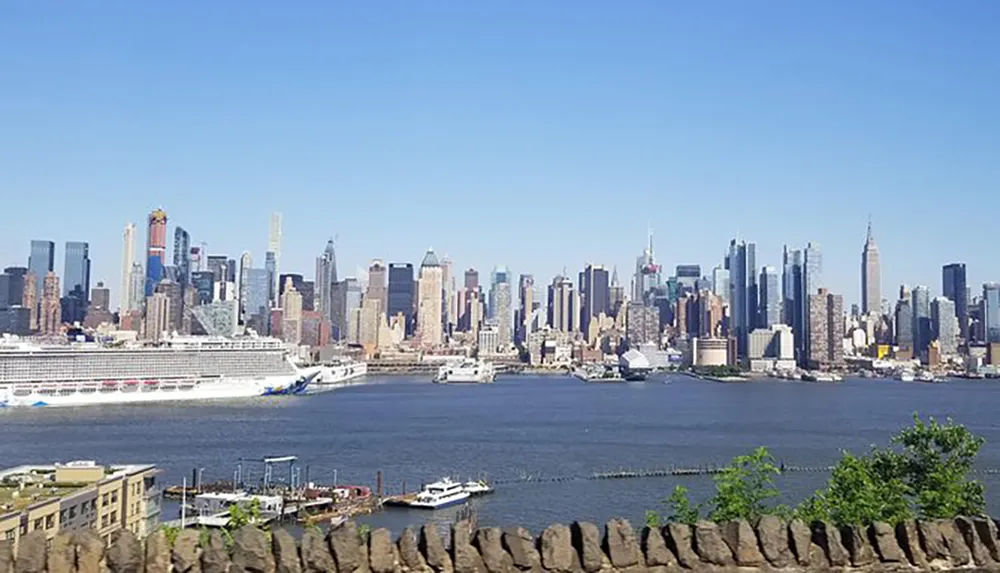 The image showcases a panoramic view of the Manhattan skyline with a large cruise ship docked on the Hudson River as seen from a vantage point with a stone railing in the foreground