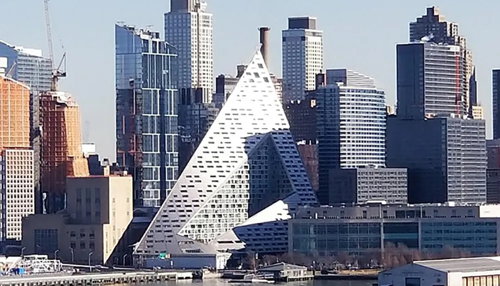 The image displays a modern city skyline with a distinctive triangular-shaped building front and center accentuating the architectural diversity among the urban landscape