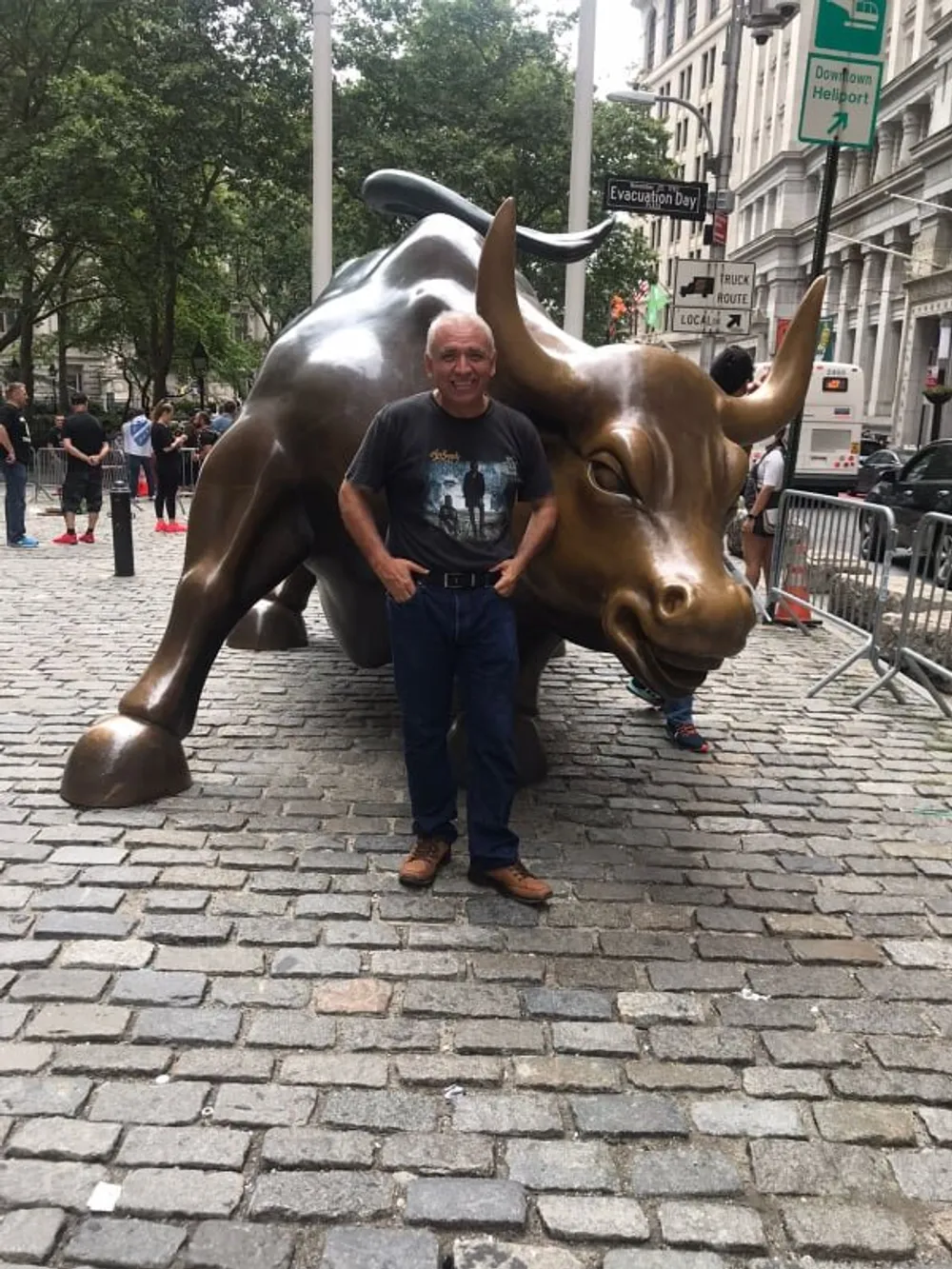 A man is standing in front of the Charging Bull statue in the financial district of New York City