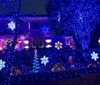A house is vibrantly decorated with colorful Christmas lights and festive inflatable decorations including Santa Claus and candy canes creating a cheerful nighttime holiday scene