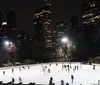 Skaters enjoy an evening on an outdoor ice rink with the illuminated backdrop of a city skyline