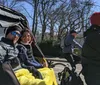 Two people are enjoying a ride in a pedicab on a sunny day with cyclists and bare trees in the background