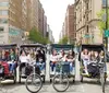 A group of people posing happily in front of a line of pedicabs likely in an urban park setting