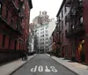 The photo captures a quiet urban street flanked by red brick buildings with fire escapes leading up to a taller building at the end with the word STOP painted in reverse on the pavement indicating the view is from the wrong way down a one-way street