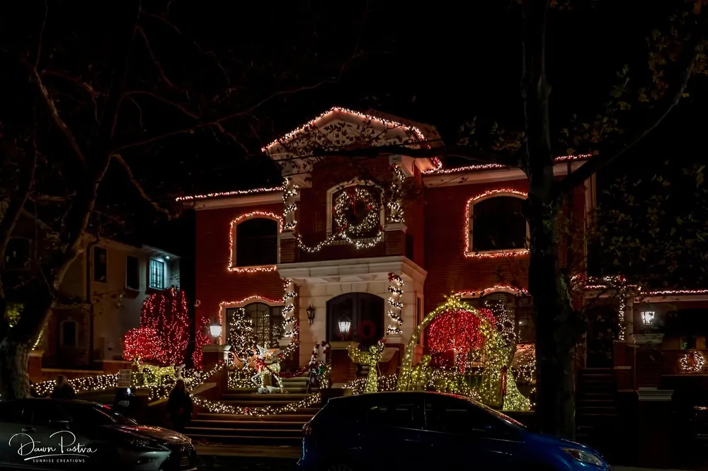 The image shows a beautifully decorated house with an intricate display of Christmas lights creating a festive nighttime scene
