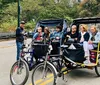A group of people enjoys a ride in pedicabs as the drivers stand by in a tree-lined outdoor setting