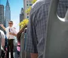 Tourists enjoy a guided bus tour with a view of the Manhattan skyline and Brooklyn Bridge under a clear blue sky