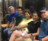 Five individuals are smiling and sitting side by side inside a subway train appearing to enjoy one anothers company