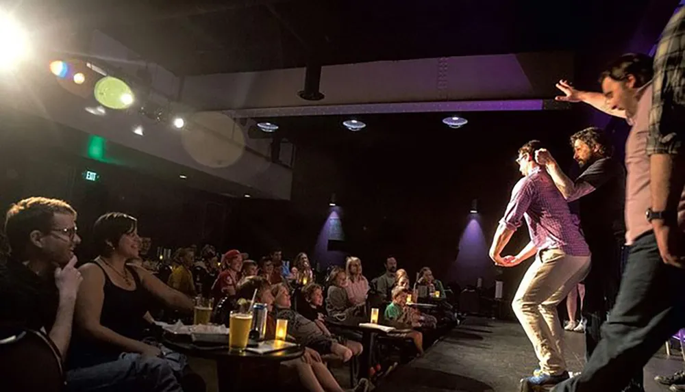 A group of performers is engaging with an audience in an intimate comedy club setting