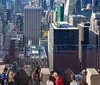 Visitors are admiring the view of a densely built-up cityscape from a high vantage point on an observation deck