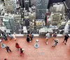 Visitors are admiring the view of a densely built-up cityscape from a high vantage point on an observation deck