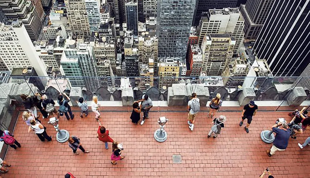 Visitors are admiring the view of a densely built-up cityscape from a high vantage point on an observation deck