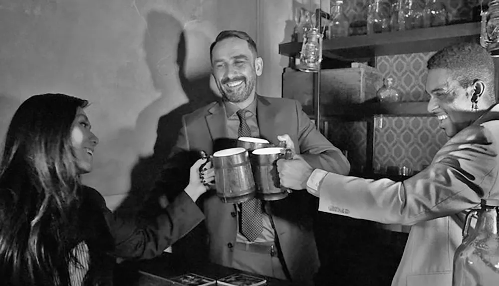 Three people are joyfully clinking beer mugs together in a friendly toast