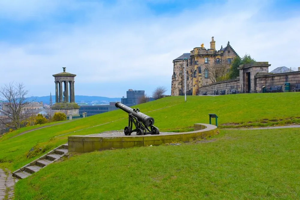 The image displays the historic Calton Hill in Edinburgh Scotland with its iconic monuments and an old cannon under a cloudy sky