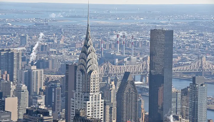 The image shows an aerial view of a cityscape dominated by skyscrapers, with an iconic art deco building in the foreground, and a bridge and river in the background.