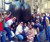 A group of people is posing and smiling at the camera in front of the Flatiron Building in New York City