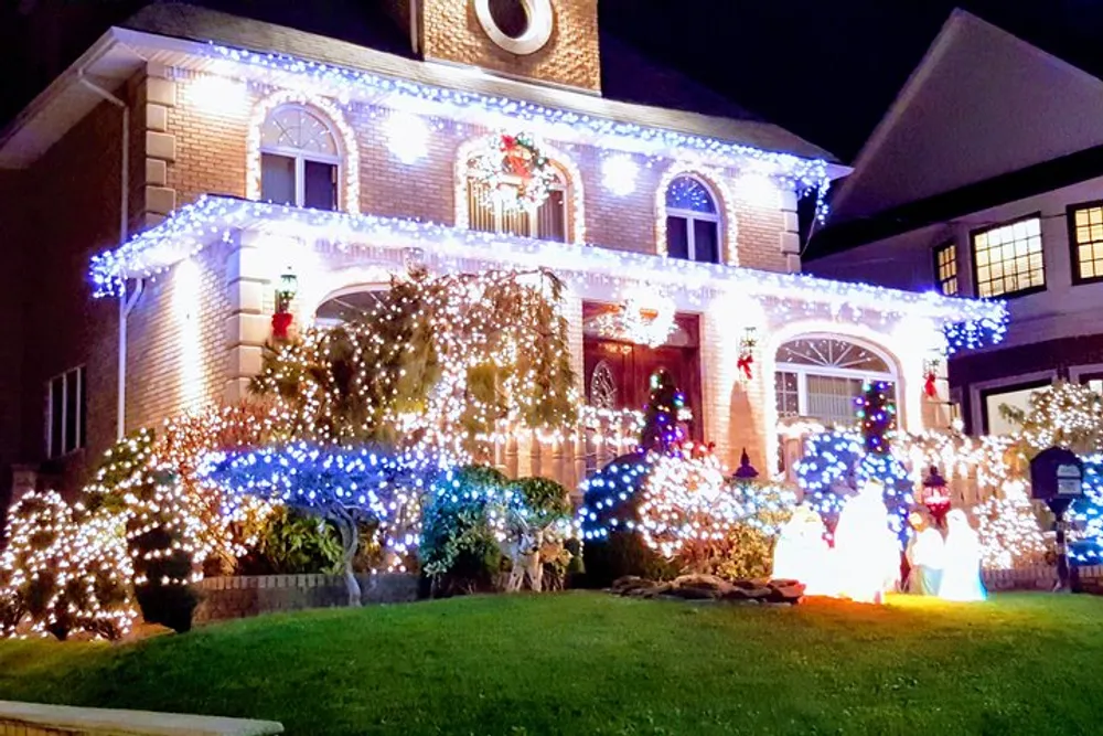 The image shows a two-story house elaborately decorated with festive lights and Christmas decorations including illuminated figures on the lawn