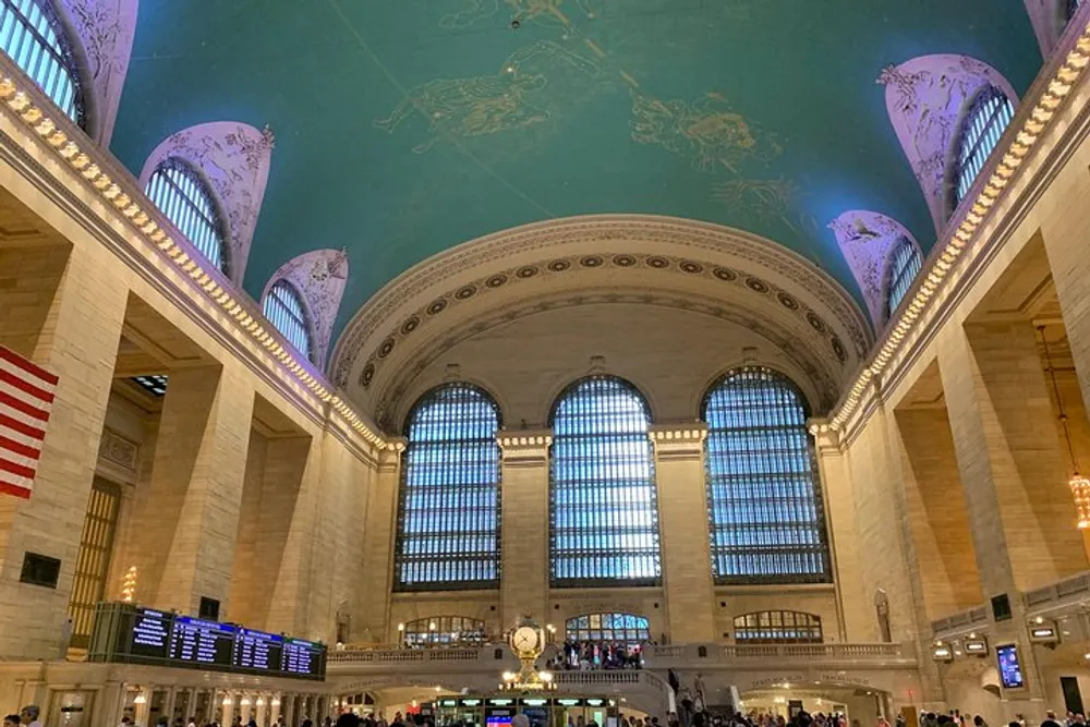 The image shows the interior of Grand Central Terminal in New York City with its expansive main concourse large windows iconic celestial ceiling and bustling atmosphere