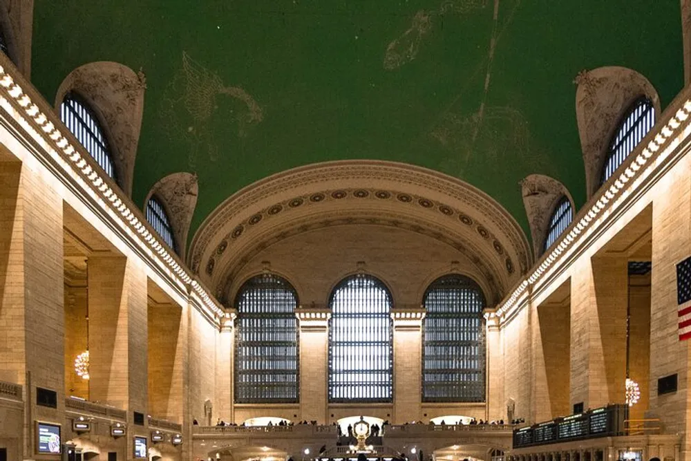The image shows the grand interior of Grand Central Terminal in New York with its soaring windows ornate detailing and expansive green ceiling