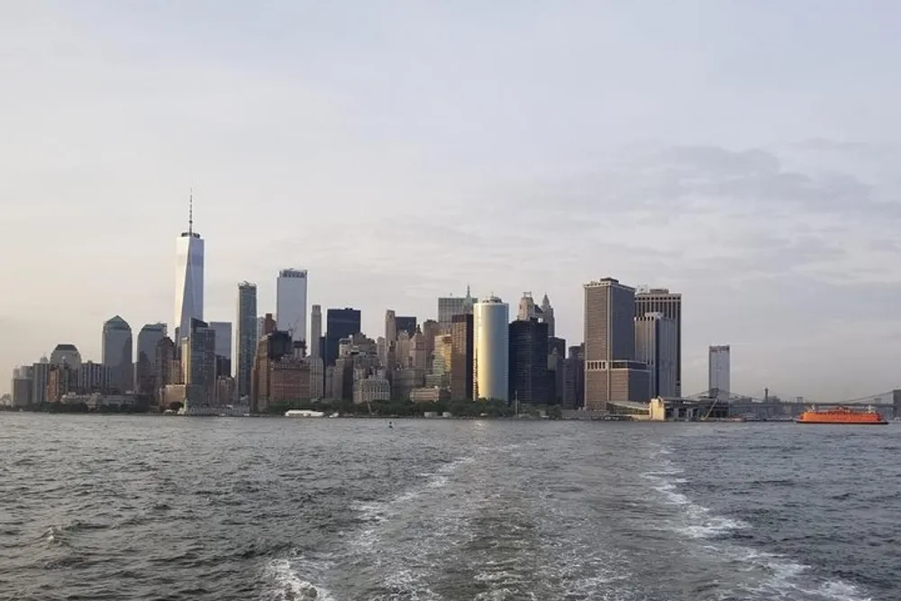 The image features a view of the Lower Manhattan skyline from the water with an orange ferry visible in the distance