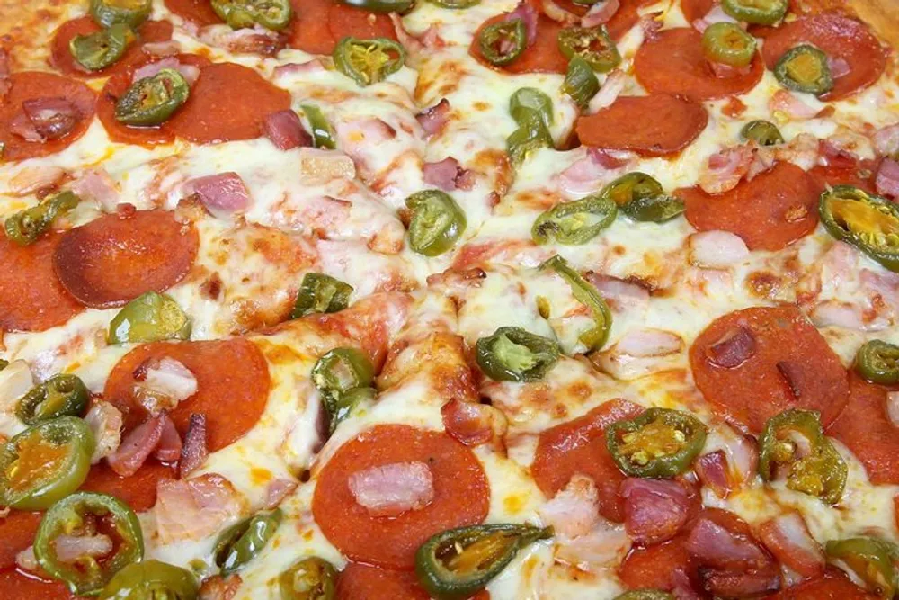 The image shows a close-up of a pizza topped with melted cheese pepperoni diced ham and sliced jalapeos