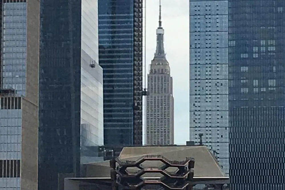 The image shows a view of the iconic Empire State Building framed by modern skyscrapers