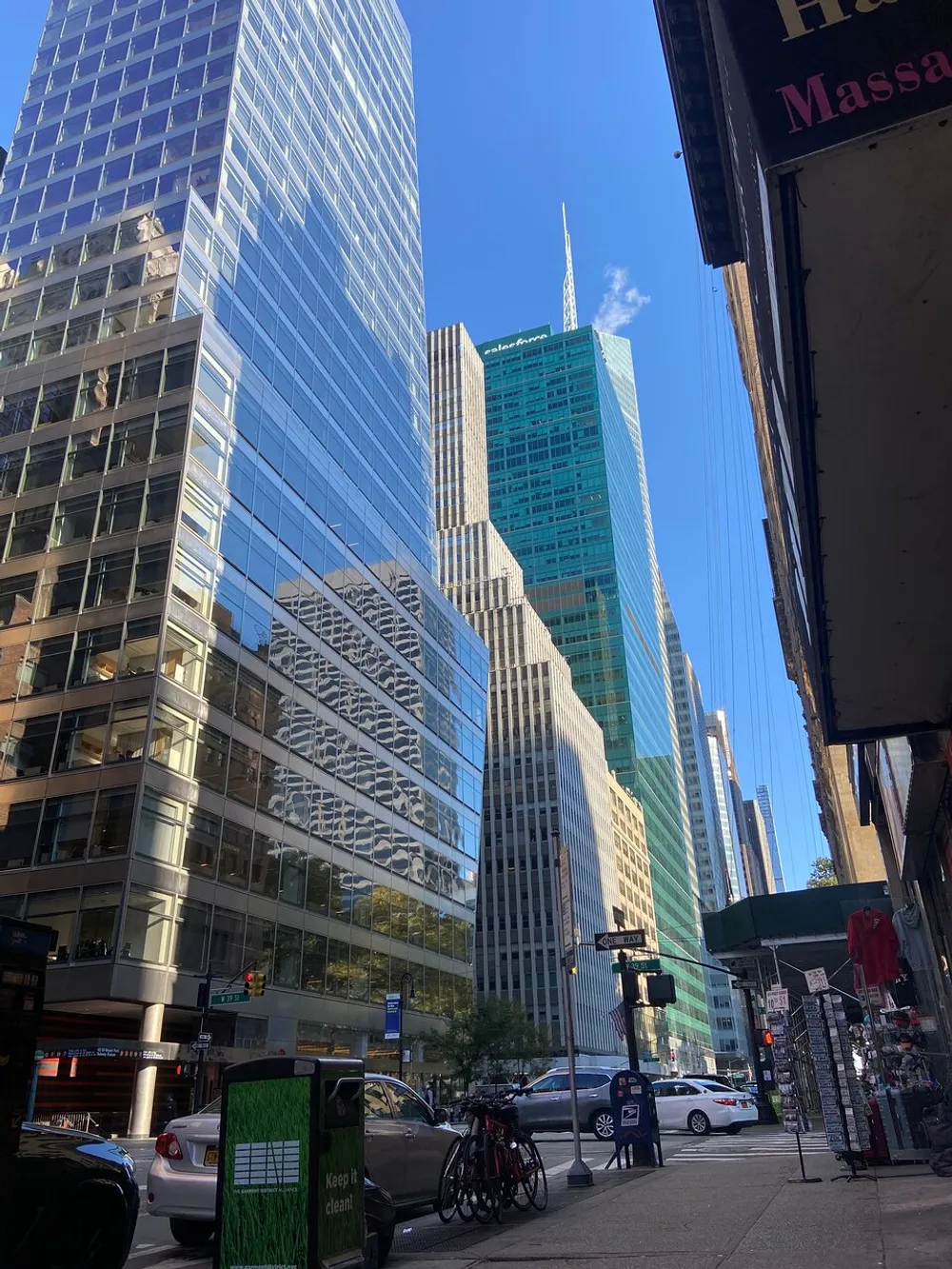 The image shows a vibrant street scene with tall skyscrapers under a clear blue sky reflecting the bustling atmosphere of a modern urban environment