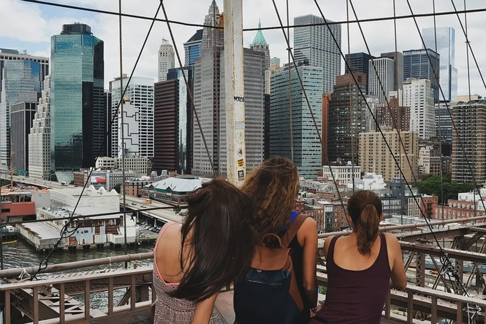 Three people are looking at a sprawling urban skyline from a high vantage point through geometrically patterned barriers