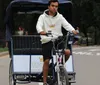 A man is pedaling a pedal-powered rickshaw on a park road appearing focused on his path ahead